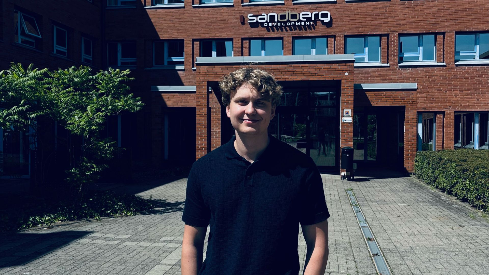 Porträttbild framför byggnad Sigurd Söberg student inom AI på Universitetet i Agder Campus Grimstad sommarjobbare på SandbergDevelopment 