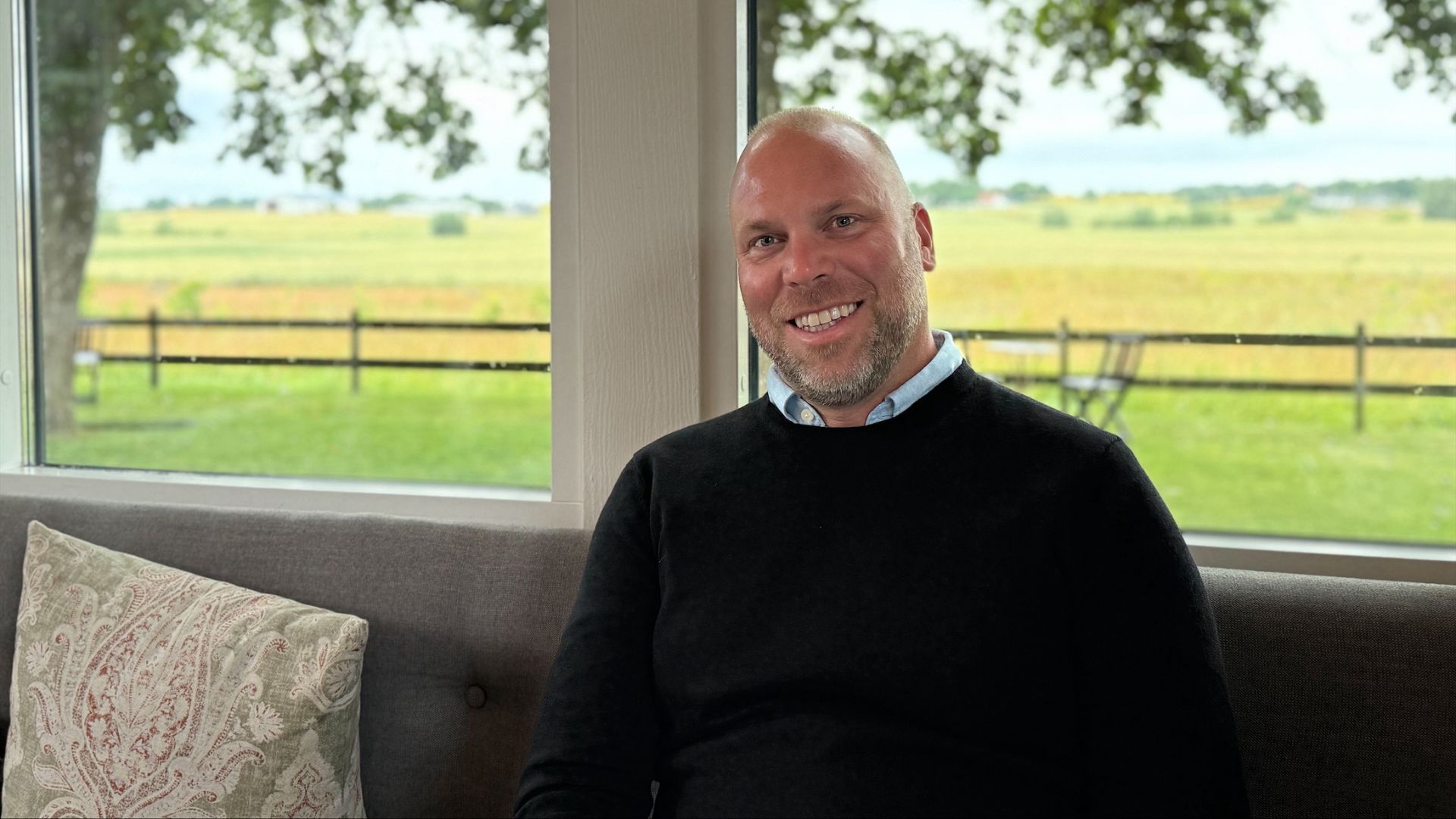 Robert Malmsten - säljare på Rescue Intellitech - sitter i en soffa och bakom honom syns en åker genom fönstret.